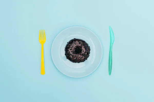 Chocolade donut op een blauwe plaat en lichtblauwe achtergrond. — Stockfoto