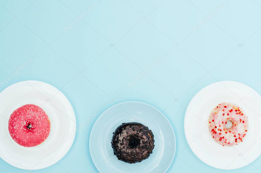Different bright donuts on a plate on a blue background. 