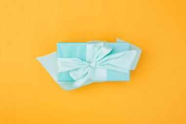 Turuncu arka planda küçük şirin bir hediye. Hediye kutusu.