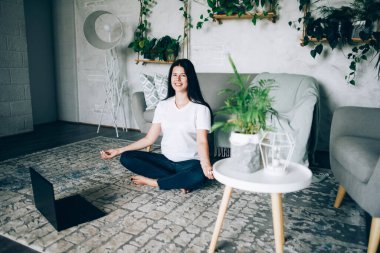 Kız evde dizüstü bilgisayarla meditasyon yapıyor..