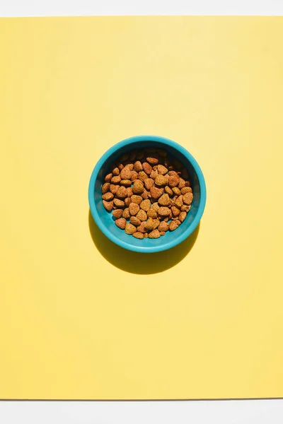 Un tazón de comida para mascotas sobre un fondo amarillo. — Foto de Stock