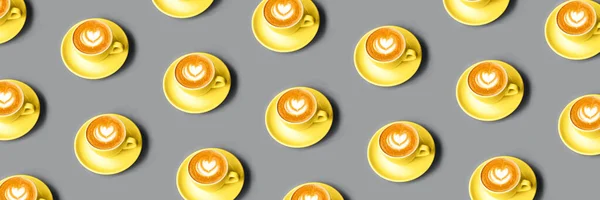 Padrão de copo amarelo de cappuccino com arte latte no fundo cinza. — Fotografia de Stock