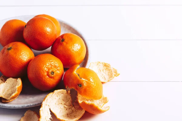 Mandarinas frescas em uma chapa cinza em uma mesa de madeira branca. — Fotografia de Stock