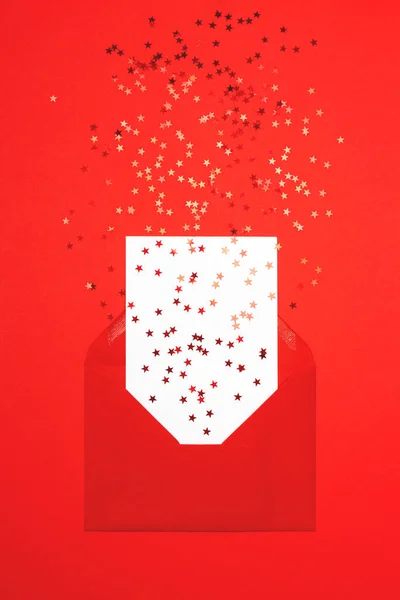 Rode confetti verspreid uit envelop op rode achtergrond. — Stockfoto