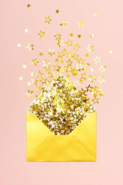 Altın konfeti pembe arka planda, zarftan yayılmış.