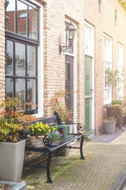 Çiçek süslemeli bir evin ön kapısının yanında bir bank..