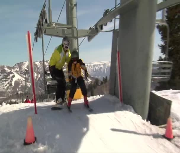 Snowboarder and small child get off chairlift — Stock Video