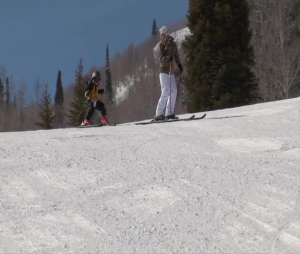 Mom leads little kid down gentle ski slope — Stock Video