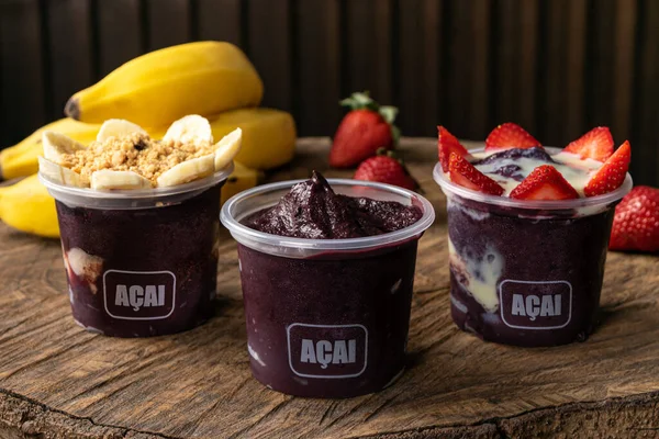 Lezzetli Brezilya Acai Kreması, çilekli, muzlu ve tahıllı bir fincanda, ahşap bir arka planda. Yaz acai smoothie