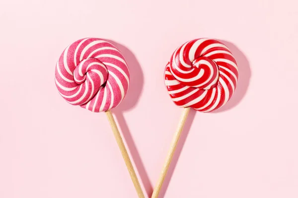 Dvě sladké lízátko cukroví na růžovém pozadí. — Stock fotografie