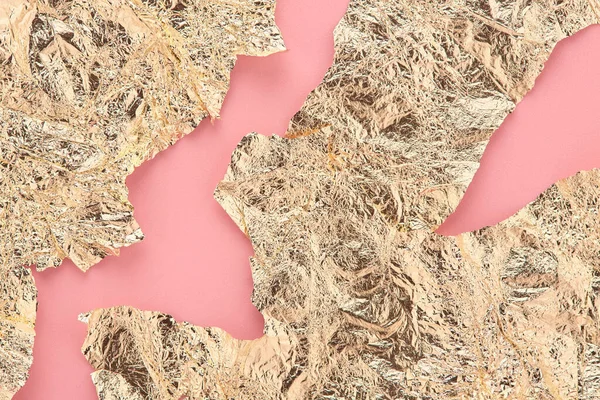 金の紙の抽象的な背景、ピンクの背景に不規則な形状の金の箔. — ストック写真