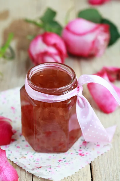 Jar of rose petal jam on a wooden table with flowers roses, sele