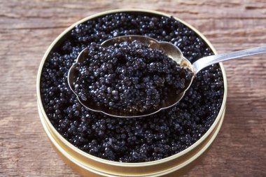 Tin can and a spoon with natural sturgeon caviar on a wooden bac