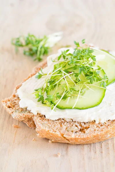 Een sneetje brood gegarneerd met waterkers, roomkaas en komkommer — Stockfoto