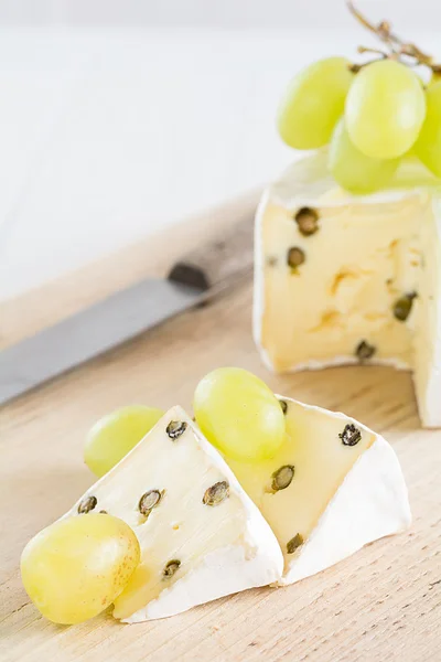 Twee stukken van Brie met groene paprika en druiven — Stockfoto