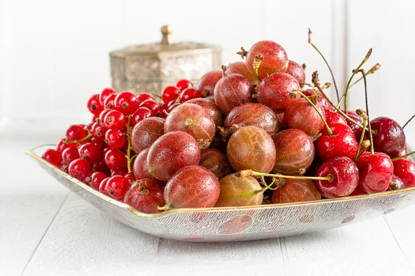 Grosellas rojas, cerezas y grosellas en un plato —  Fotos de Stock