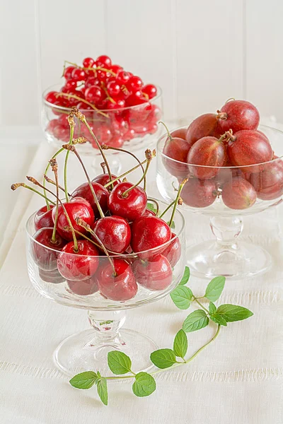 Körsbär, krusbär och röda vinbär i glas — Stockfoto