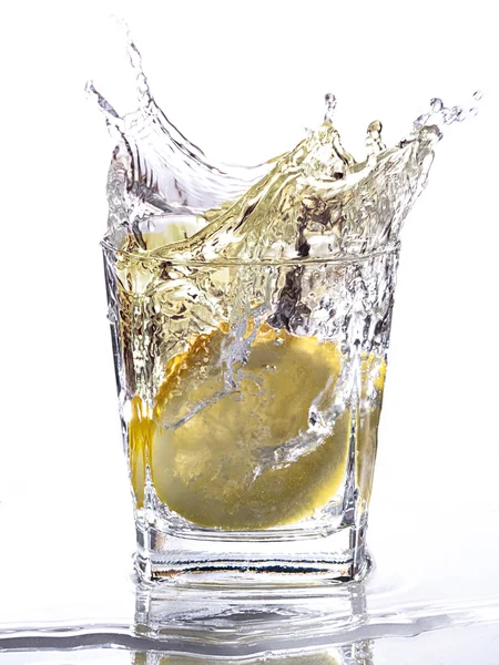 A slice of lemon falls into a tumbler — Stock Photo, Image