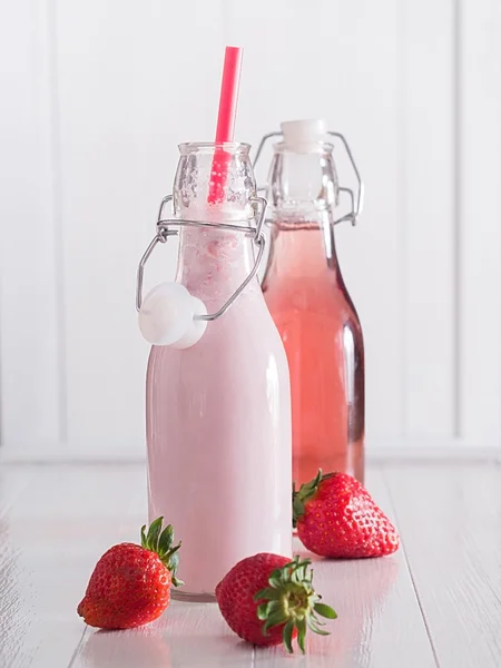 Jordgubbsjuice och jordgubbar mjölk i flaskor Royaltyfria Stockbilder