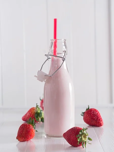 Melk met aardbeien in een fles Stockfoto