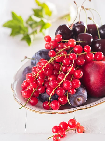 Groselhas vermelhas, cerejas e pêssegos em uma tigela — Fotografia de Stock