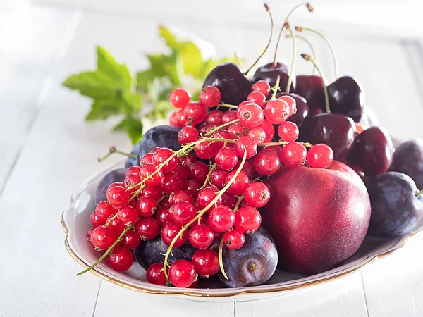 Grosellas rojas, cerezas y melocotones en un tazón —  Fotos de Stock