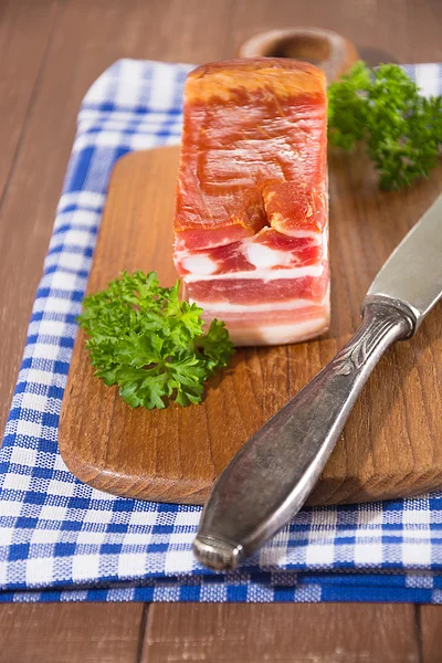 Tocino ahumado en una tabla de madera —  Fotos de Stock