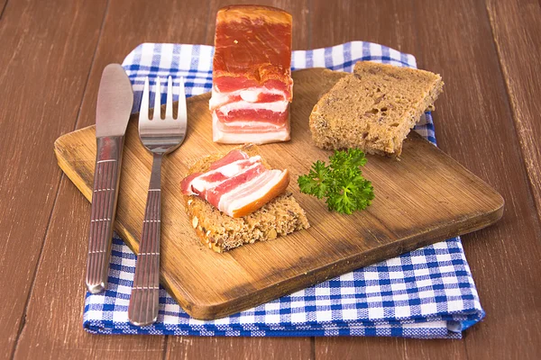 Tocino ahumado en una tabla de madera — Foto de Stock