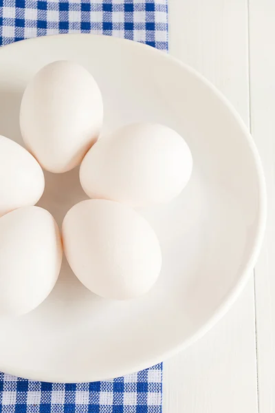 Os ovos crus estão em uma chapa — Fotografia de Stock