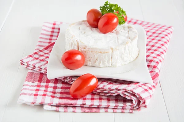 Um Camembert redondo em uma placa branca — Fotografia de Stock