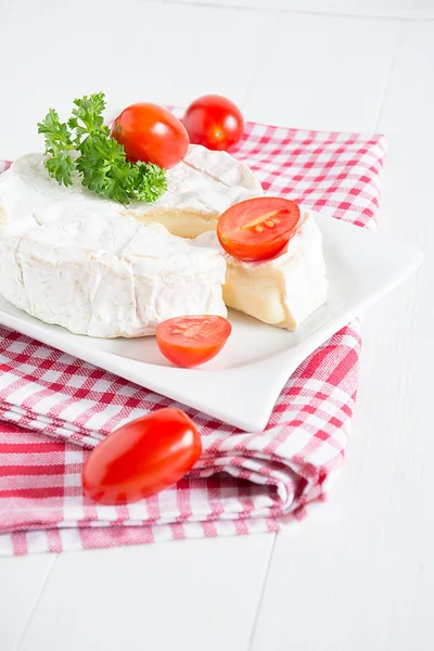 Um Camembert redondo em uma placa branca — Fotografia de Stock