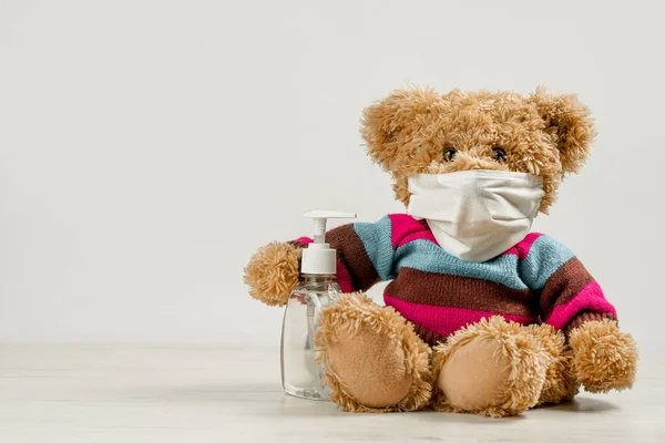 Oyuncak ayı yüz maskesi takıyor ve dezenfektan tutuyor. Kreş ya da okul posteri konsepti. Çocuklar için endişe, çocuklar için endişe. Boşluğu kopyala