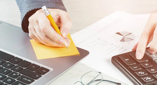 Finans ve iş konsepti. Dişi küçük işletmeler. Masa ve dizüstü bilgisayardaki mali grafiklerde hesap makinesiyle el ele. Muhasebe bütçesi ya da piyasa analizi. Ev ekonomisi. Krediler