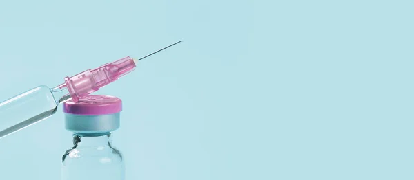 one glass syringe with a needle on blue . copy space close up view. Medication safe consumption and treatment, vaccine and immunization. Health and pharmacy concept banner