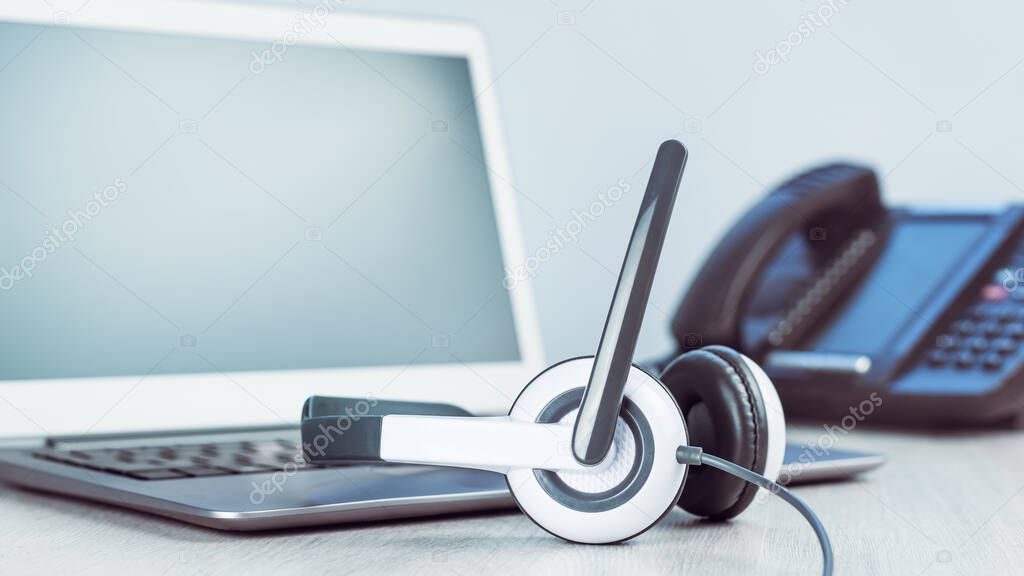 business and communications. Mockup laptop and voip phone in the office. Webinar or online conference. laptop with headset on desk. IP telephony, Cold calling. Office work or learning. Copy space