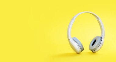 Kablosuz, modern, gri kulaklıklar sarı arka planda dikiliyor. Aydınlatıcı. Uzaktan öğrenme, müzik veya radyo dinleme. Boşluğu kopyala
