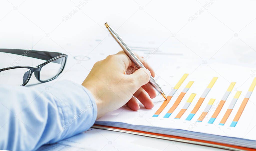 Finance and business concept. Hand pointing at statistics chart. calculator on financial graphs on desk. Female small business. Accounting budgeting loans or market analysis. Business growth