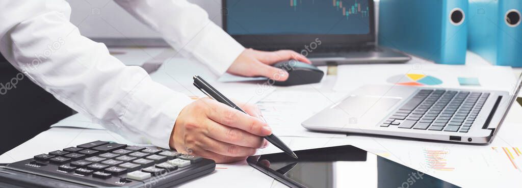 Stock exchange trade and forex financial concept. Laptop with graphs on desk with copy space. Hand with calculator. Distant learning or broker working from home or office, online business.
