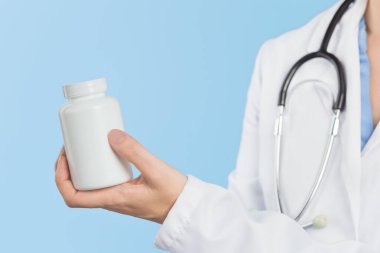 Kadın doktorun elinde beyaz haplar ya da tablet kavanozunun maketi var. İlaç ve eczane, reçeteli ilaçlar veya vitamin konsepti. Boşluk afişini kopyala