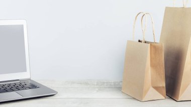 Cilalı kağıt alışverişi yapan dizüstü bilgisayar modeli gri renkli çantalar taşıyor. İnternet üzerinden mal ve market teslimatı, internet alışverişi. Çevre ve çevre dostu ambalaj, plastik ücretsiz servis. Kilitlenme