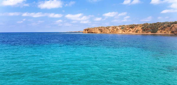 View of rocky coast turquoise sea waters on a sunny day with blue sky. Blue lagoon. Destination scenics seascape. Travel and adventure. Cyprus. Mediterrenian. No people. Vivid web banner