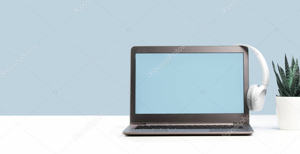 Laptop. Mockup screen and headphones on white desk and plain background banner. Distant learning. working from home, online courses or support minimal concept. Helpdesk or call center headset