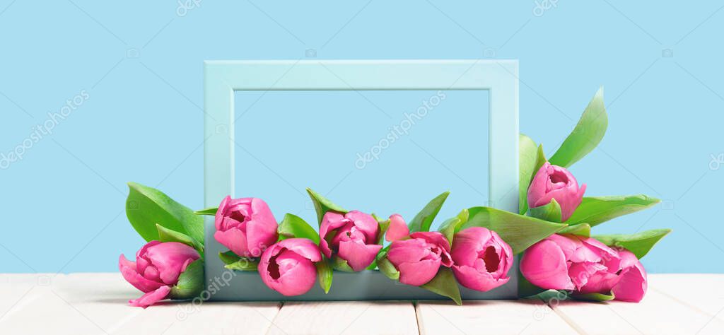 Bunch of pink tulips in a frame on wooden table. Banner with copy space, Birthday gift. Valentines 8 March Women's or Mothers Day celebration greeting card or framed web floral. Spring