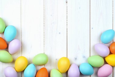 Ahşap zemin üzerinde birkaç parlak renkli paskalya yumurtası fotokopi alanı ile düzleştirilmiş. Mutlu Paskalyalar için Asgari Konsept Kart veya Pankart Sınırı