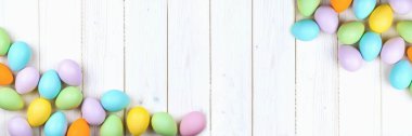 Ahşap zemin üzerinde birkaç parlak renkli paskalya yumurtası fotokopi alanı ile düzleştirilmiş. Mutlu Paskalyalar için Asgari Konsept Kart veya Pankart Sınırı