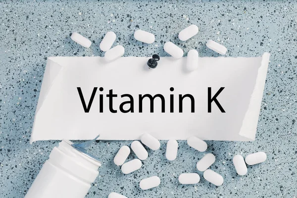 Not panosundaki K vitamini metni. Etrafa hap ve tabletler saçılmış.
