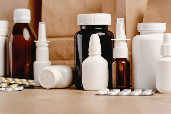 Online pharmacy. prescription drugs and over the counter medication ready for delivery to customers. Pills and spray white mockup containers and buff paper bags on table. Drugstore shopping