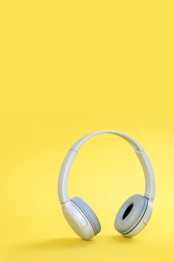 Kablosuz, modern, gri kulaklıklar sarı arka planda dikiliyor. Aydınlatıcı. Uzaktan öğrenme veya müzik dinleme veya radyo yayını veya sohbet. Boşluğu kopyala