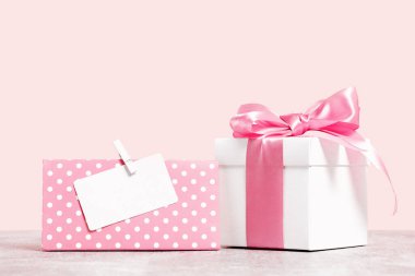 Pembe arka planda pembe kurdeleli beyaz hediye kutusu ve sahte Gitf kartı. Hediye ya da tatil konsepti. Anneler Günü, doğum günü düğünü ya da fotokopi çekilen Sevgililer Günü afişi