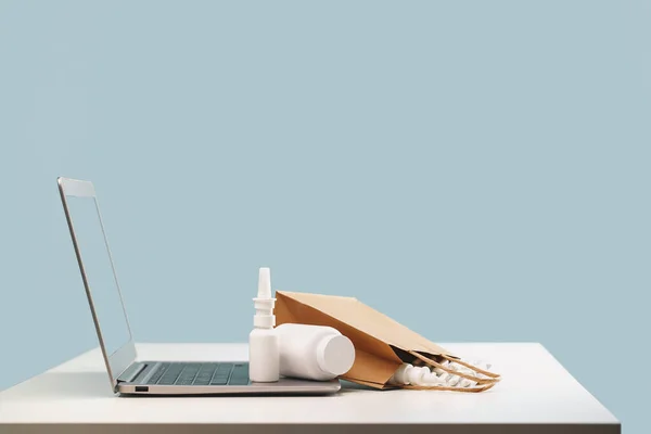 İnternetteki eczane. Reçeteli ilaçlar ve reçetesiz ilaçlar müşterilere ulaştırılmaya hazır. İlaçlar ve beyaz maket kaplar sprey ve cilalı kağıt torbaları dizüstü bilgisayarın üzerine. Eczane alışverişi